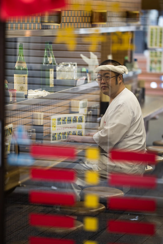Ramen chef sits on restaurant stool-Narrative light and color mentorship