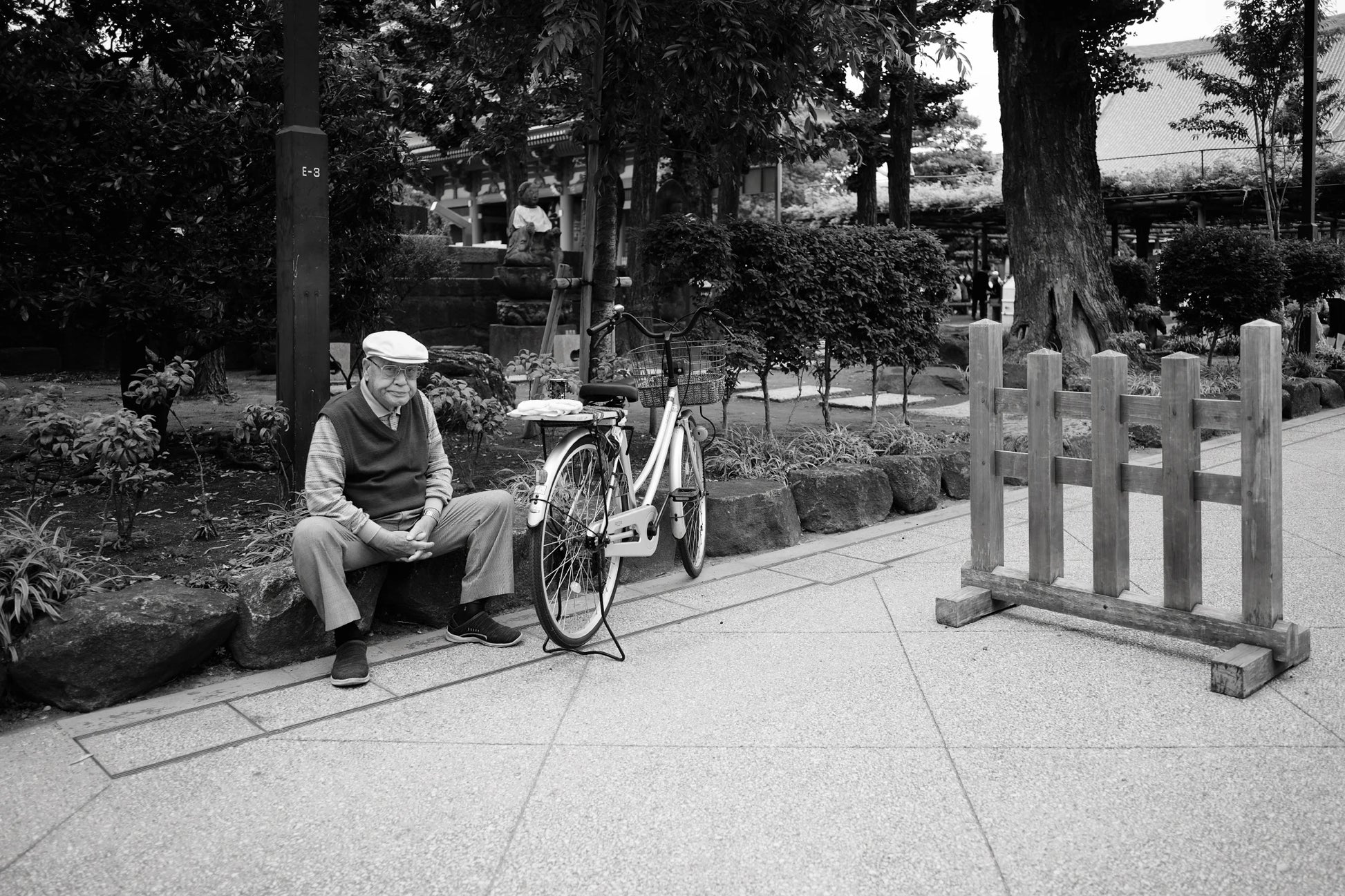 Environmental portraiture in Tokyo park of an old man sitting next to a bicycle.