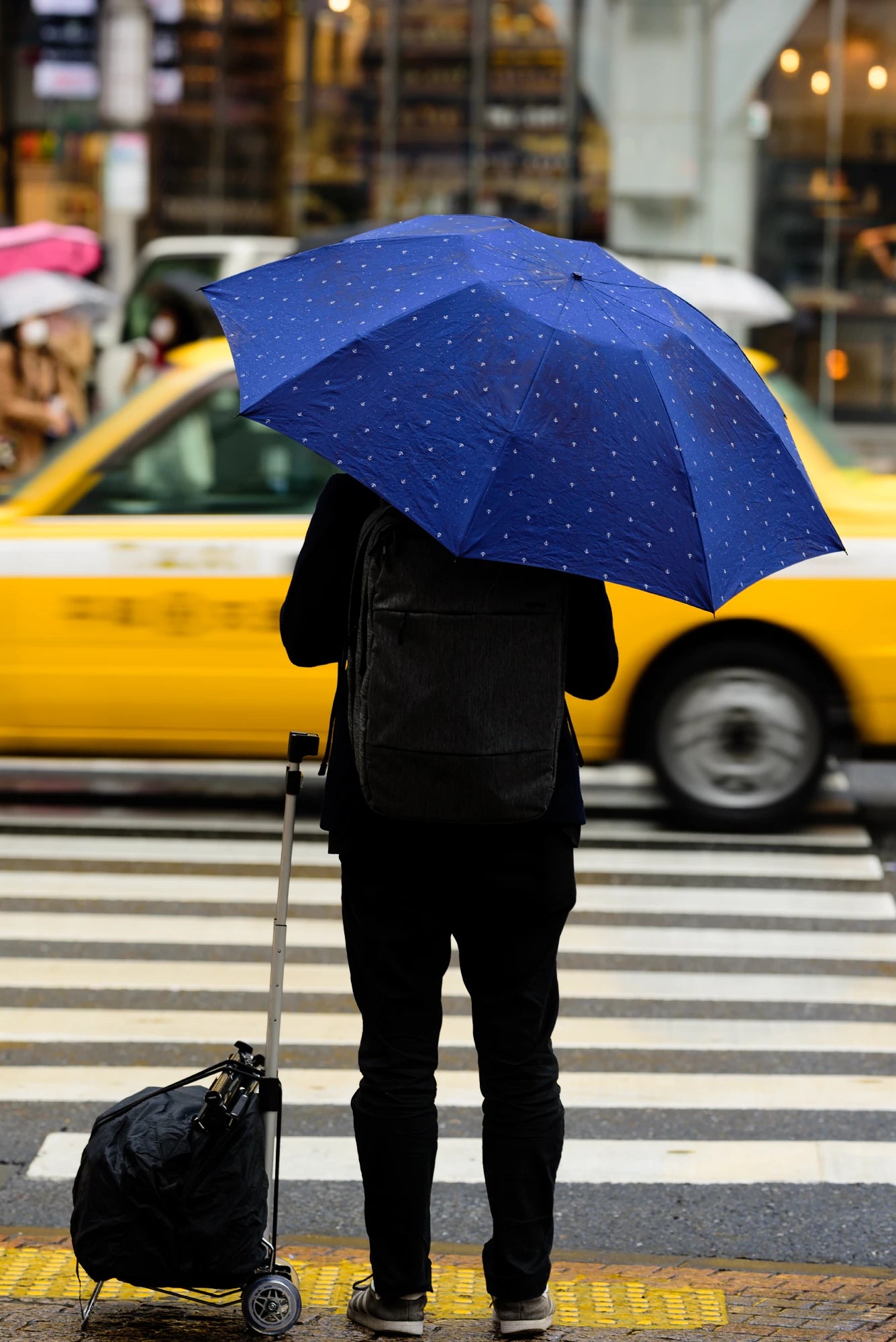 Man with blue umbrella next to a yellow taxi-Urban color theory for photographers